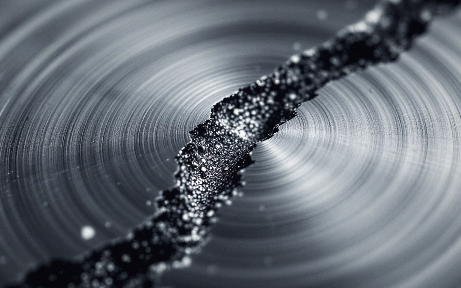 A fracture surface photographed under a lamp, beach marks and final overload zone visible