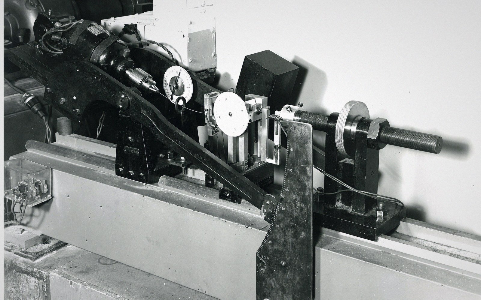 Vintage fatigue-testing apparatus with gauges and a metal shaft mounted on a rail bed
